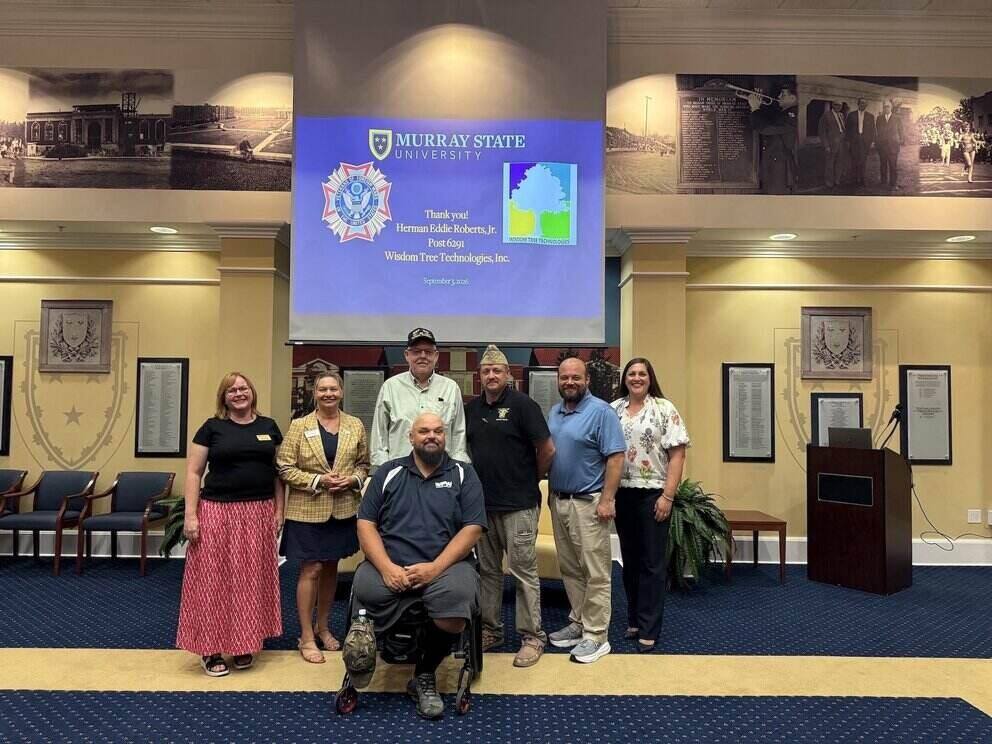 group of people standing in front of veteran backdrop 
