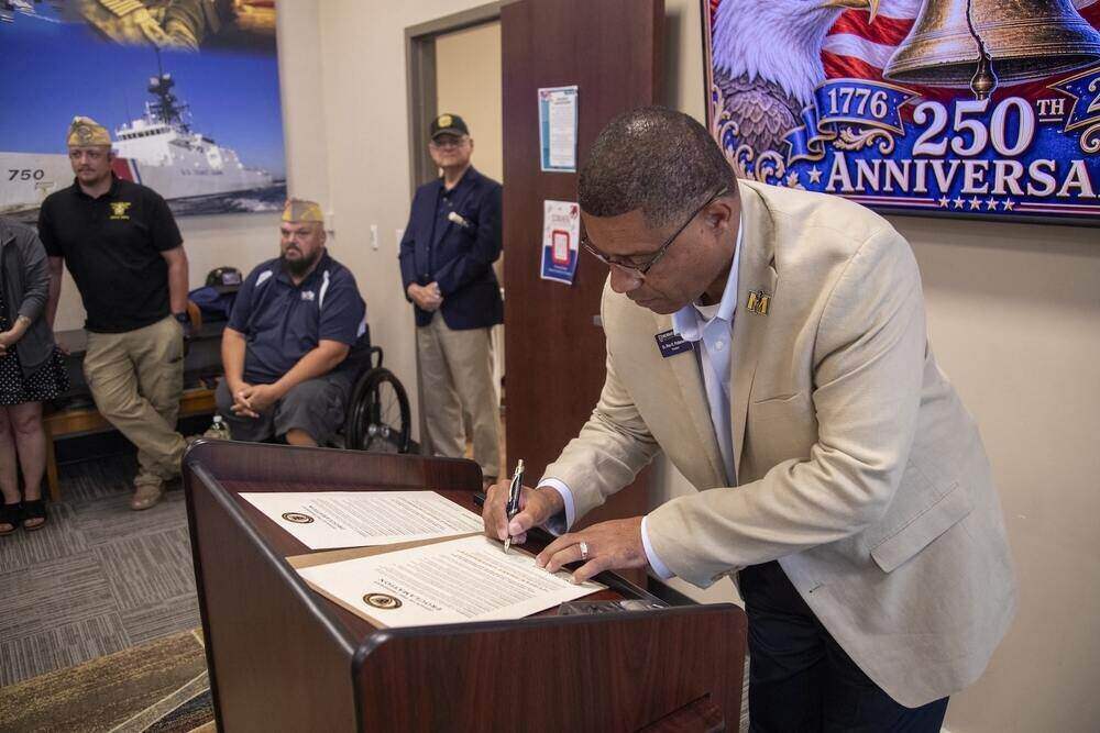 Dr. Ron Patterson signs a Purple Heart University proclamation for Murray State University in front of a group of veterans