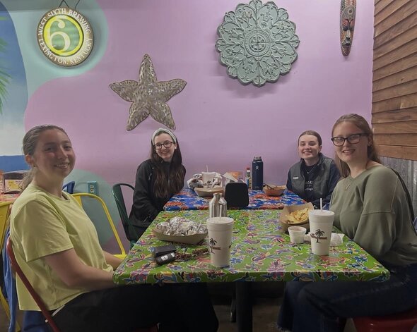 four students seating around table