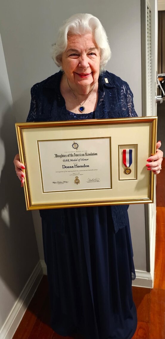 Donna Herndon holding a Daughters of the American Revolution Medal of Honor award