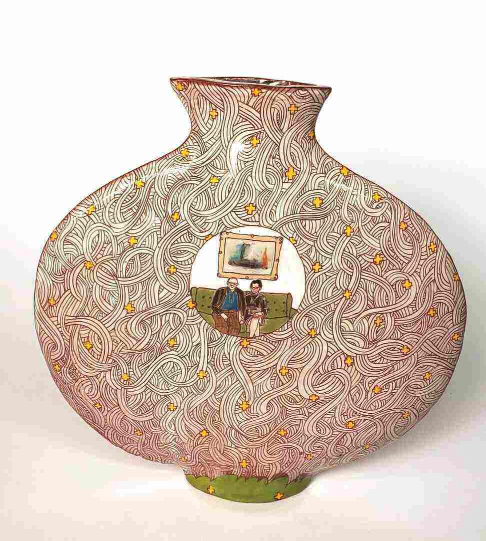 A wide ceramic vase with a green base and a portrait of an elderly couple on a couch in the center.