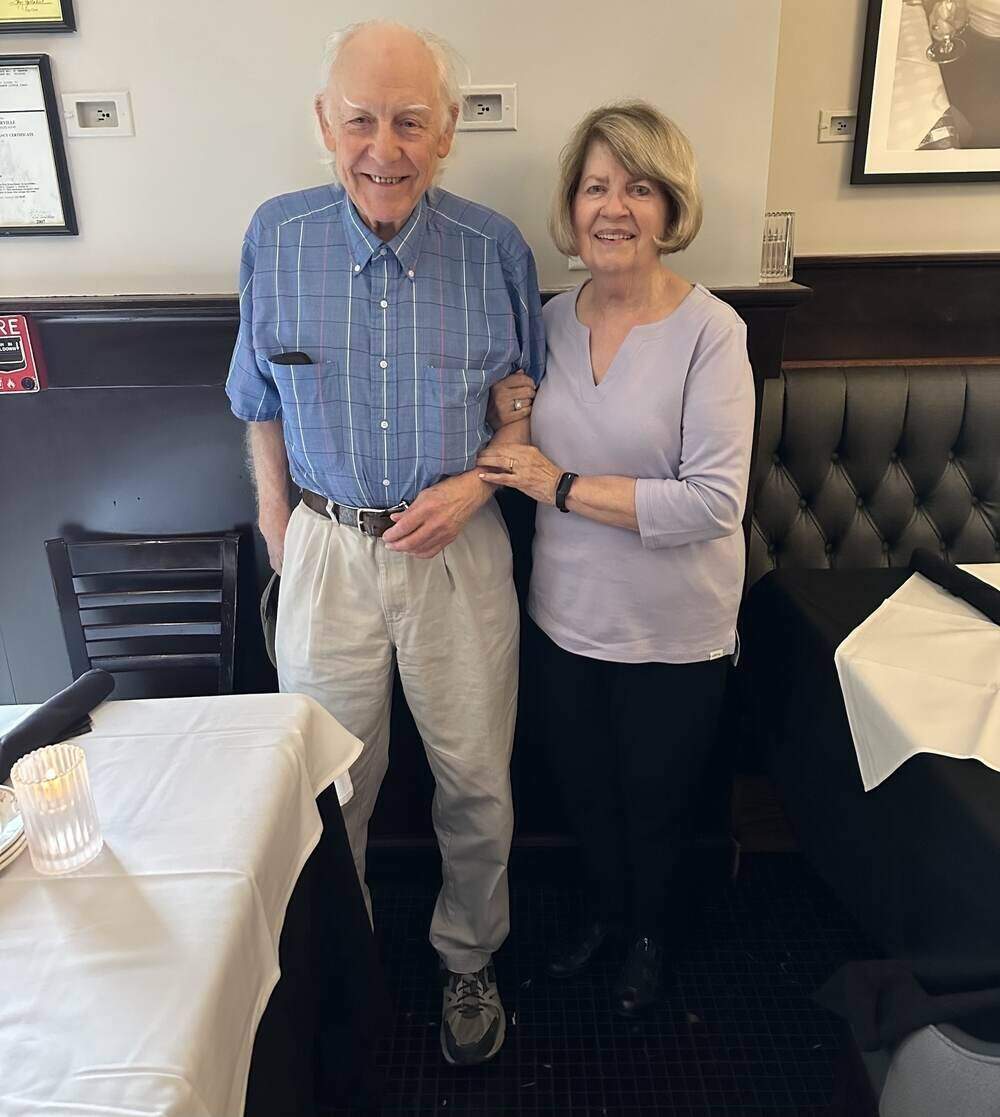 A man in a blue shirt on the left and a woman in a lavender top on the right.