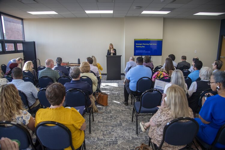 Dr. Elise Kieffer speaks in front of a group of people with a screen beside her.