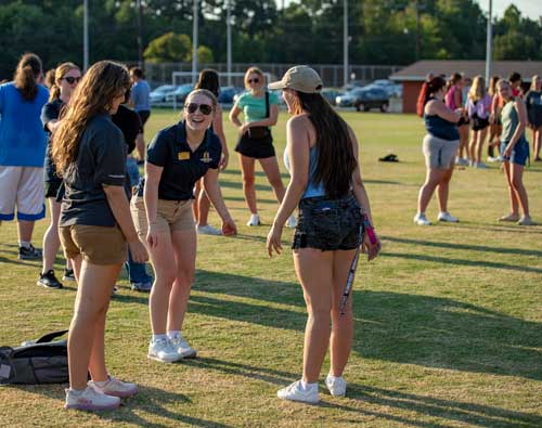 an admissions counselor leads two students in a cheer on the intramural fields