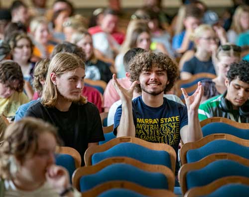 A student looks at the camera and holds his hands up in Lovett Auditorium for the Blue and Gold Celebration